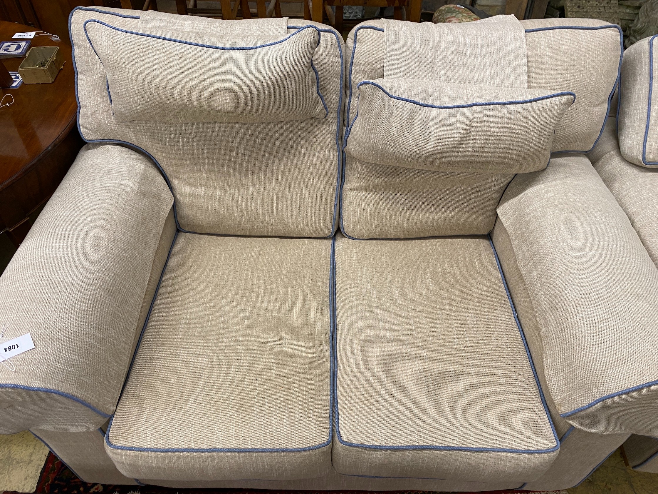 Two cream upholstered settees, with blue corded edging, larger length 200cm, depth 100cm, height 97cm